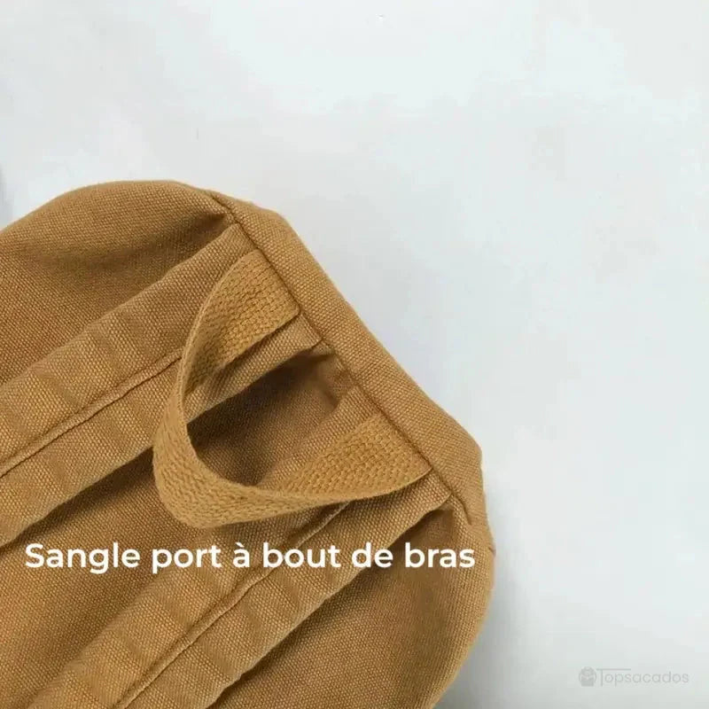 Sac à dos toile marron avec gros plan sur la sangle de port à bout de bras, fond blanc