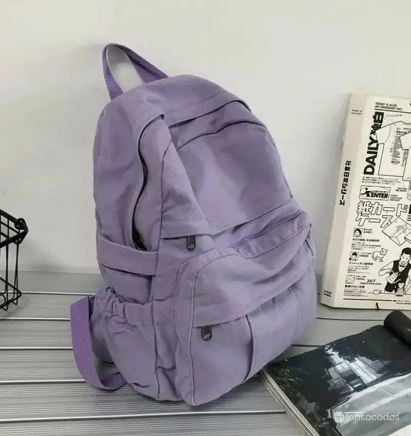 Sac à dos toile violet vu de trois quarts sur une table à côté de journaux japonais