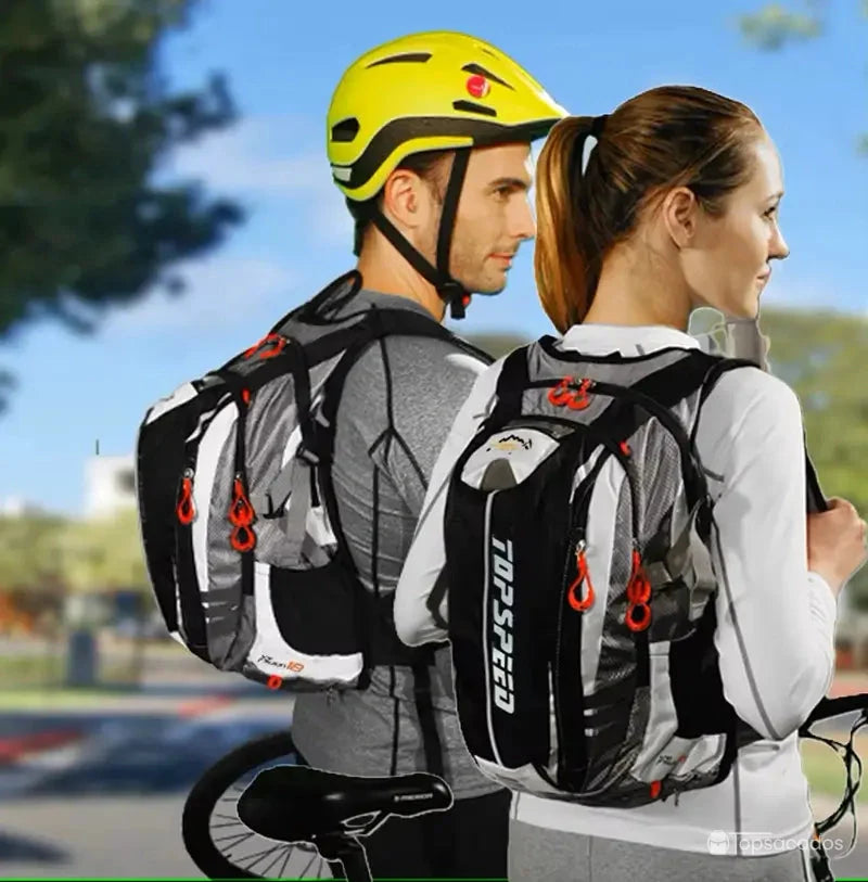 Sac à dos vélo avec poche à eau porté par un couple de cyclistes en tenue, dans un environnement urbain, illustrant un usage quotidien.