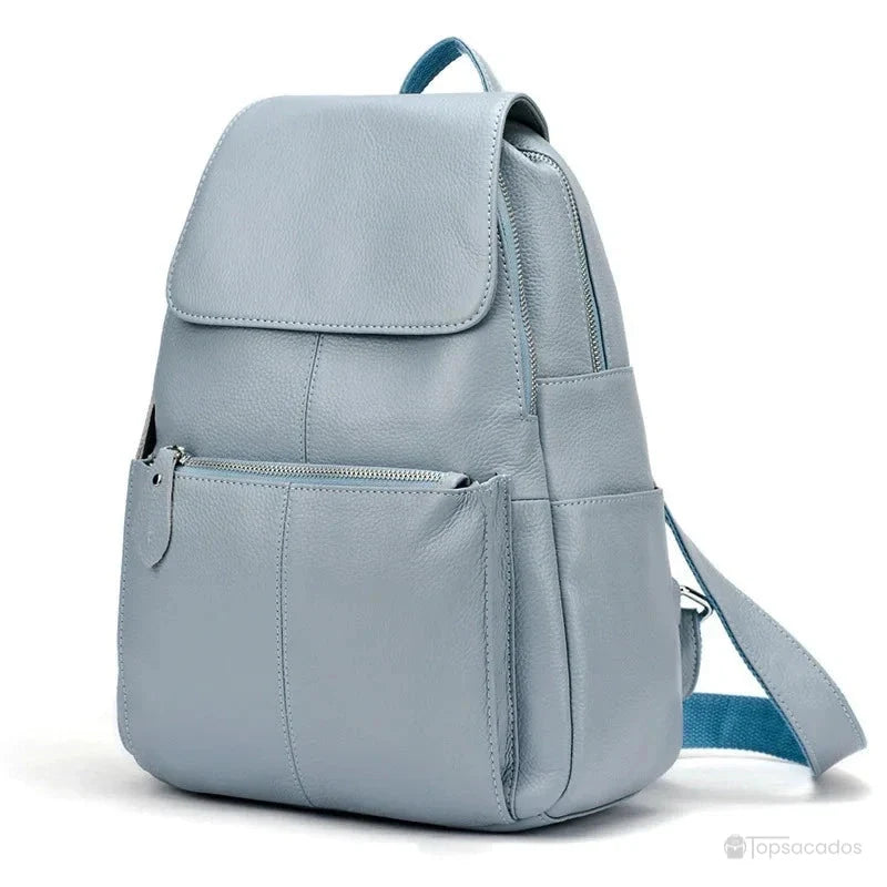 sac à dos ville femme bleu gris en cuir lisse, avec rabat souple et poche zippée à l’avant, positionné en trois-quarts sur fond blanc