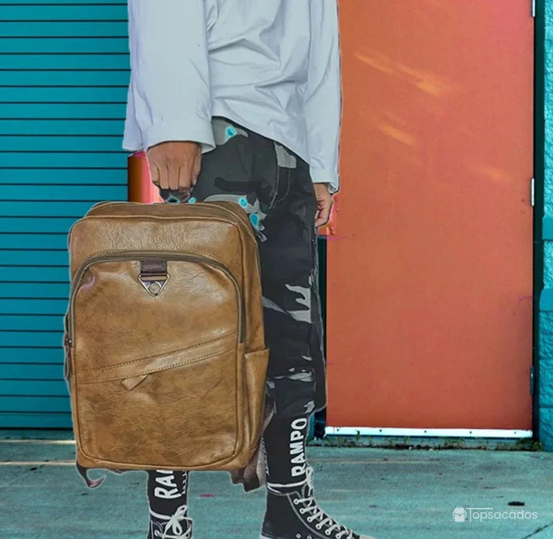 Sac à dos ville homme porté à la main par un homme en tenue urbaine, en environnement citadin coloré.