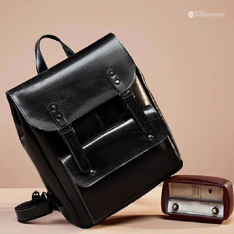Sac à dos vintage pour femme noir incliné contre une radio rétro sur fond beige, apportant une ambiance rétro chic à la scène.