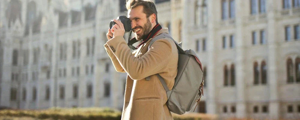 Sac a dos voyage – Homme photographiant un monument historique avec un sac à dos gris lors d’un city trip en Europe