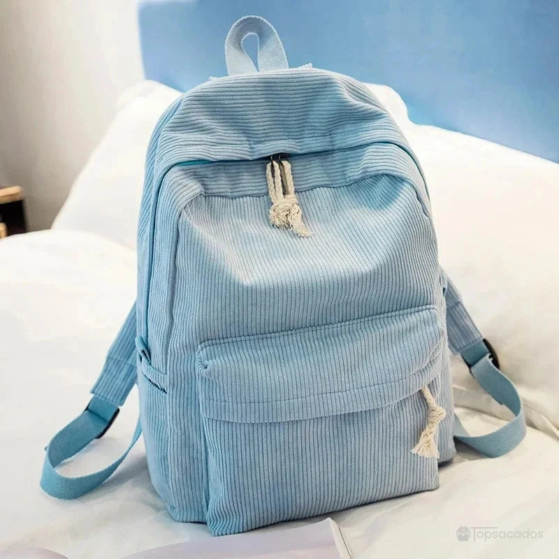 sac à dos college en velours cotelé bleu clair, vu de trois quarts sur un lit, ambiance chambre cosy