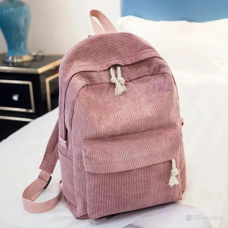 sac à dos college en velours cotelé rose vintage posé sur un lit, ambiance douce et féminine