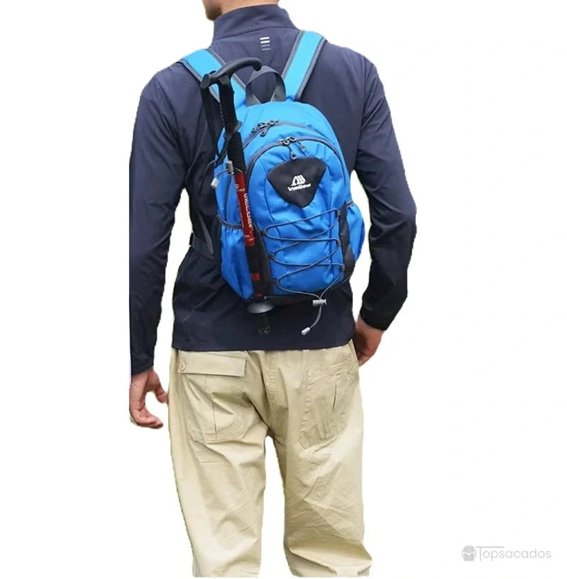 Petit Sac à dos randonnée bleu avec bâton fixé sur le côté, porté par un homme vu de dos en extérieur.