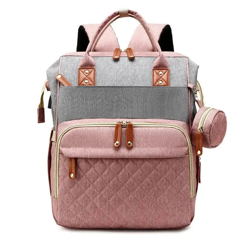 Sac à dos à langer avec port usb bicolore rose et gris, vu de face avec finitions marron et pochette latérale, sur fond blanc.