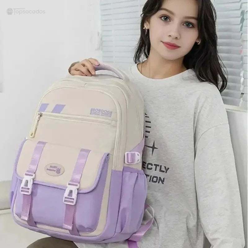 Sac à dos ado beige et violet tenu par une jeune fille en intérieur, montrant le format confortable et les finitions soignées