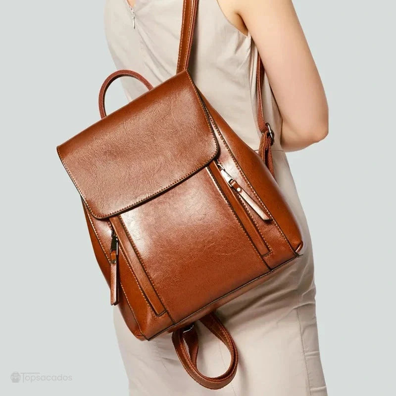 Sac à dos antivol Femme cuir marron porté à une épaule par une femme, avec fond gris clair, mettant en avant l'élégance du sac.