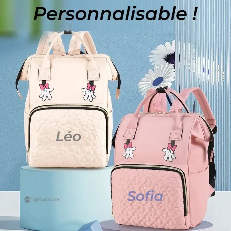 sac-a-dos-bebe-avec-son-prenom personnalisable avec prénom brodé Léo et Sofia, présenté dans un décor pastel avec socles cylindriques bleus et fleurs décoratives