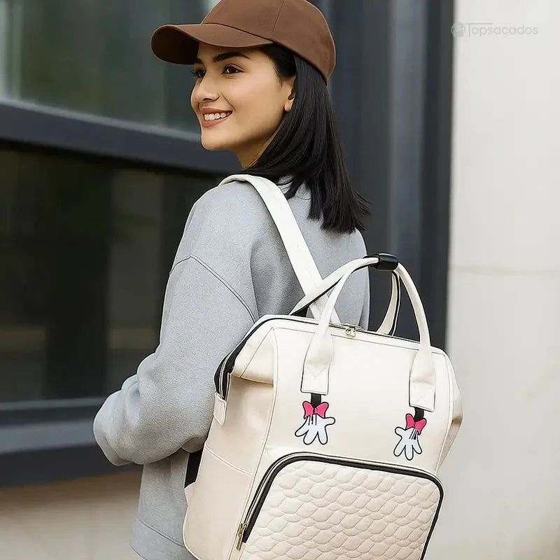 sac-a-dos-bebe-avec-son-prenom beige porté par une femme souriante, en extérieur urbain