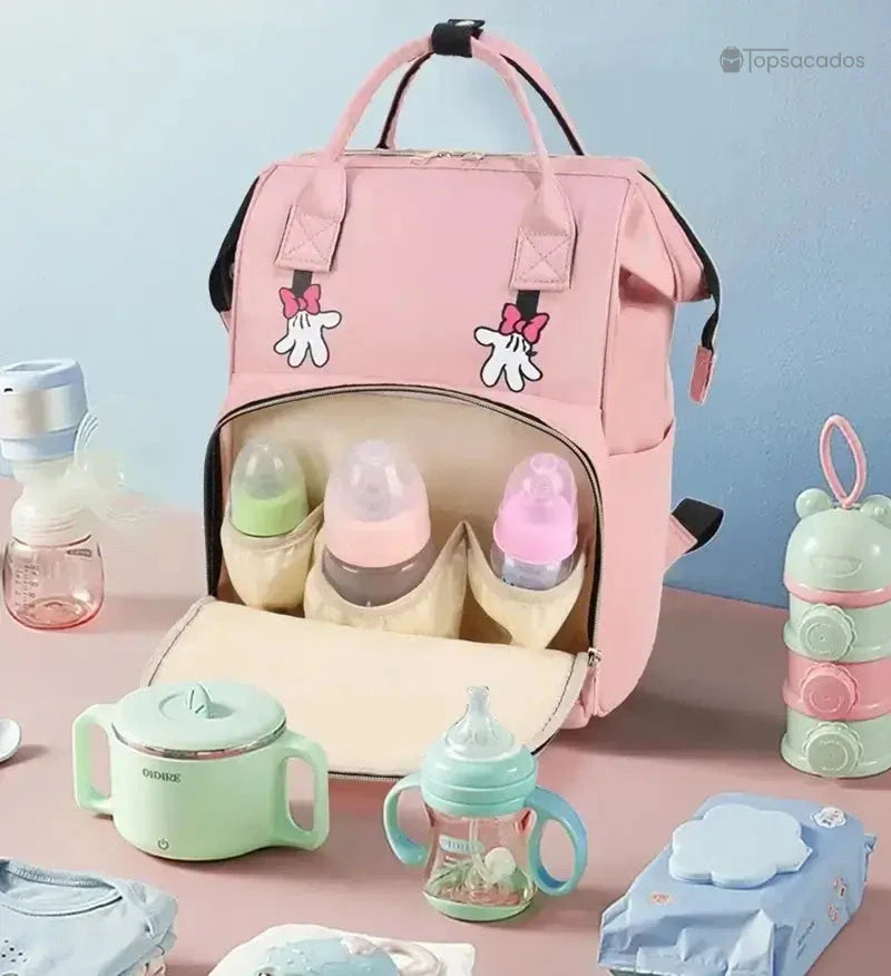 sac-a-dos-bebe-avec-son-prenom rose ouvert, posé sur une table avec accessoires de bébé autour