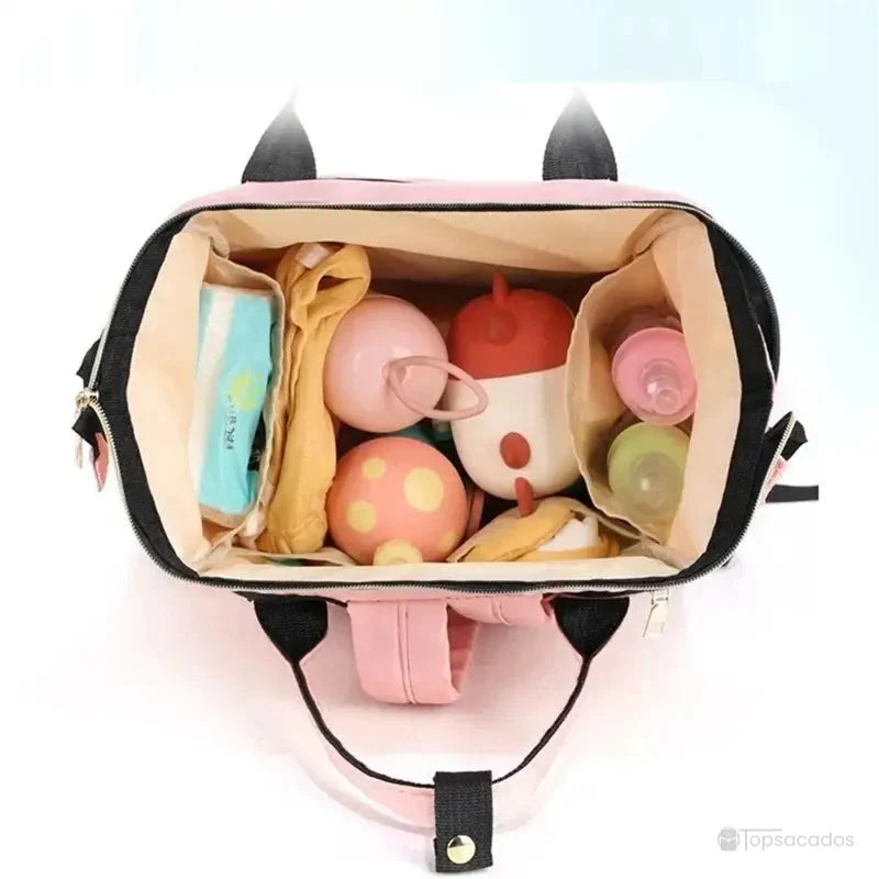 sac-a-dos-bebe-avec-son-prenom rose vu de dessus avec jouets, biberons et lingettes bien rangés à l’intérieur