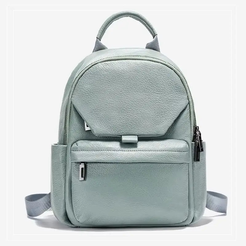 Sac à dos cuir femme vert clair vu de face, avec grande poche avant zippée et design arrondi, posé sur fond blanc.