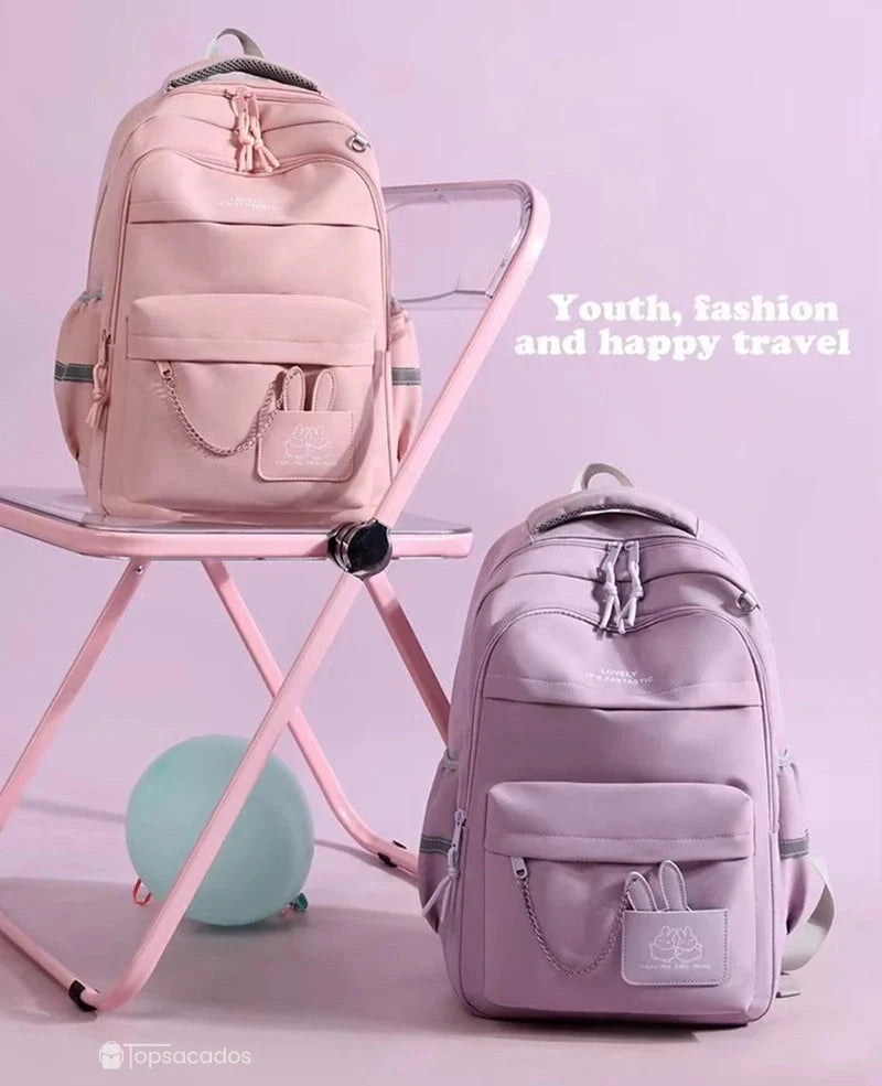 Sac à dos école deux sacs pastel posés sur une chaise rose dans un décor intérieur rose pastel.