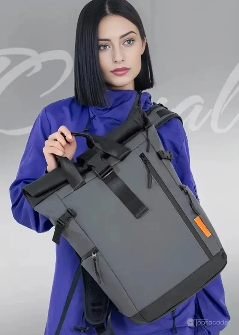 Sac à dos étanche porté à la main par une femme en manteau violet sur fond clair, mettant en valeur son design élégant et sa solidité.