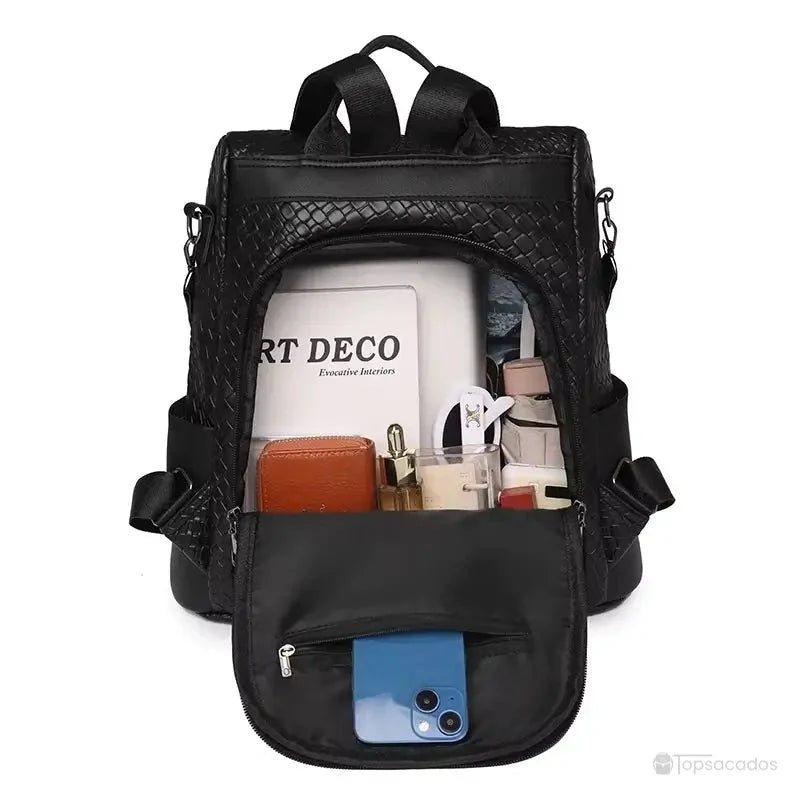 Sac à dos femme noir rempli d’accessoires, illustrant la capacité à contenir un livre A4, smartphone, portefeuille et produits de beauté.
