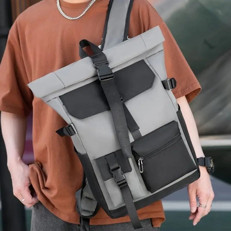 Sac à dos à fermeture enroulable porté en bandoulière par un homme en t-shirt marron, illustrant l’allure moderne et la tenue structurée du sac en usage urbain.