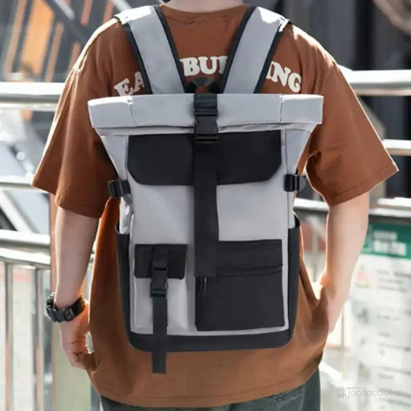 Sac à dos à fermeture enroulable porté sur le dos par un homme en extérieur urbain, mettant en évidence son maintien stable et son design ergonomique.