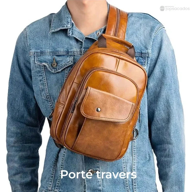Sac à dos homme cuir de vachette porté en travers sur la poitrine par-dessus une veste en jean, mode urbaine et pratique, sur fond blanc.