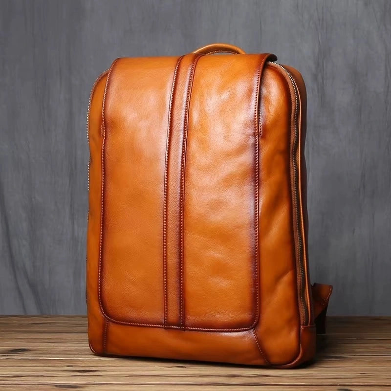 Sac à dos homme cuir marron vu de face, design élégant avec lignes verticales de couture en cuir, posé sur sol en bois.