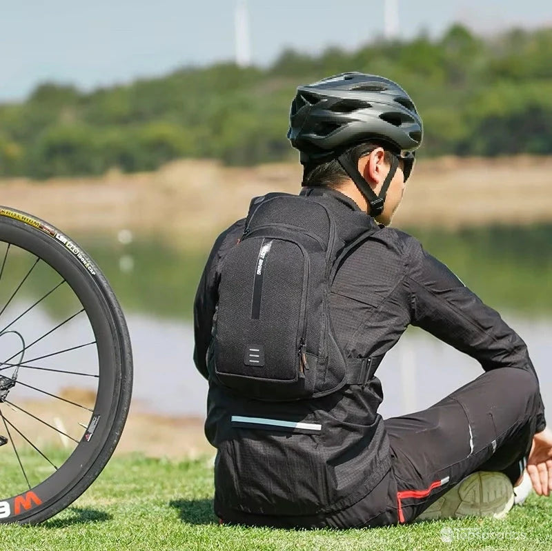 sac à dos hydratation 2 litres porté par un cycliste assis en extérieur près d’un lac, casque sur la tête, avec une roue de vélo visible au premier plan