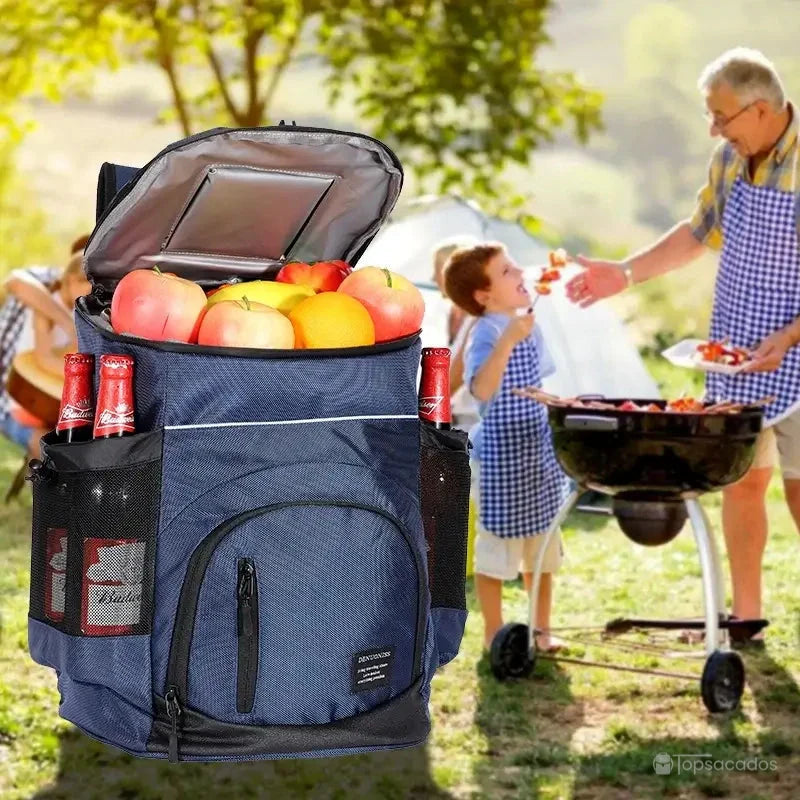 Sac à dos isotherme bleu rempli de fruits et boissons, utilisé pendant un barbecue familial en plein air dans un environnement estival.