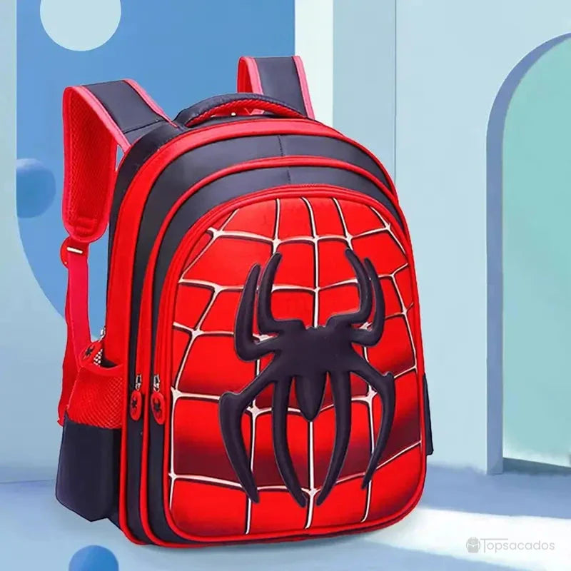 Sac à dos maternelle araignée rouge posé dans un décor bleu clair, avec lumière naturelle entrant par une arche.