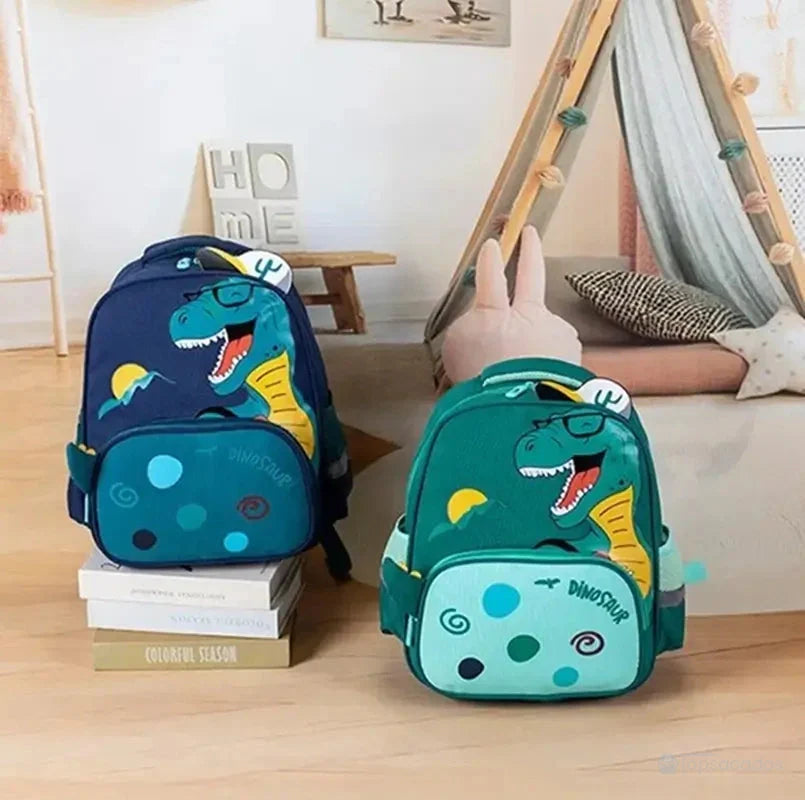 Sac à dos maternelle dinosaure en situation dans une chambre d’enfant avec tipi, peluche et éléments décoratifs chaleureux.