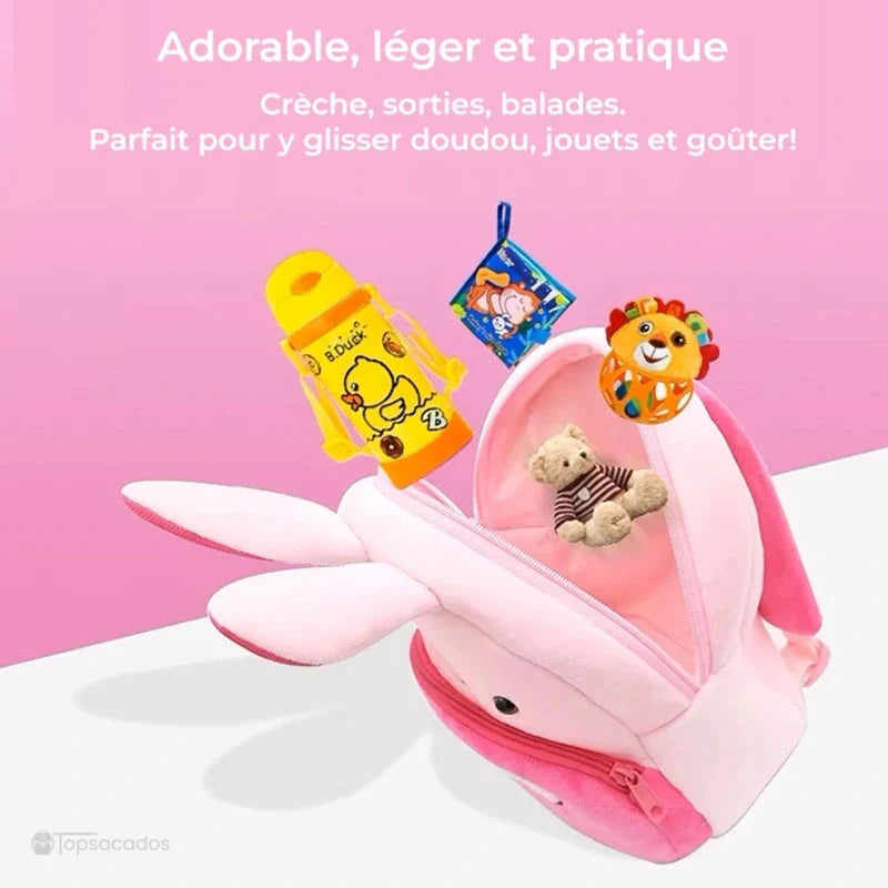 Sac à dos maternelle fille rose avec oreilles de lapin ouvert contenant un jouet, un doudou et une bouteille, sur fond rose décoratif.