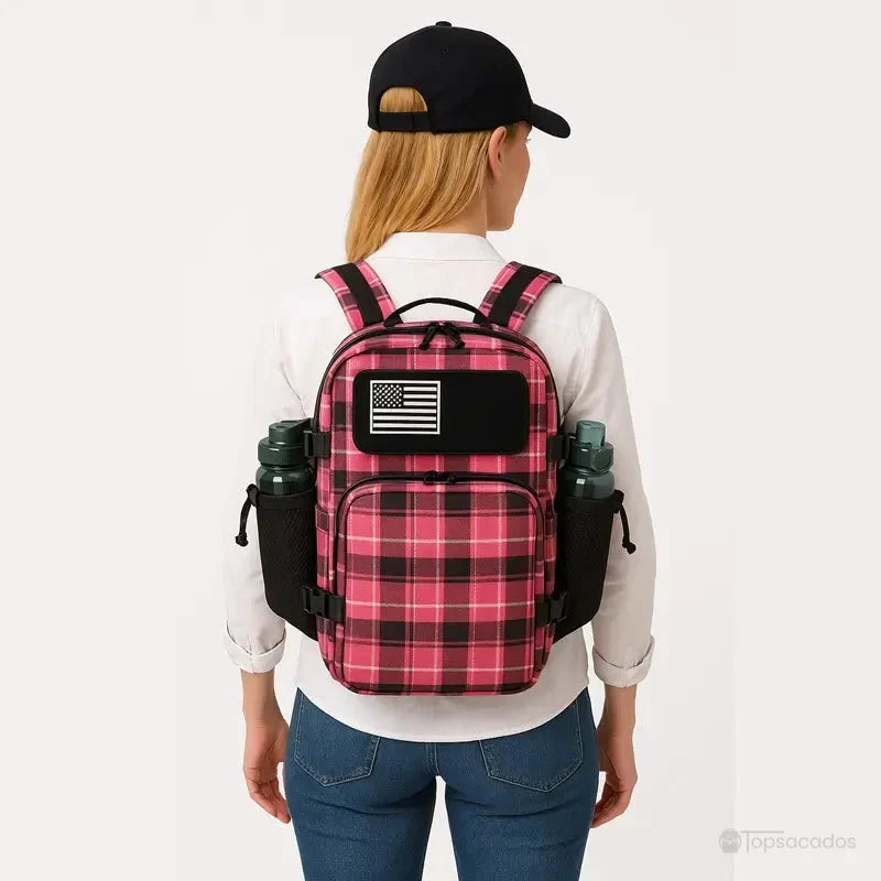 Femme vue de dos portant un sac à dos militaire rose à motif écossais avec patch drapeau américain, vêtue d'un jean et d'un chemisier blanc