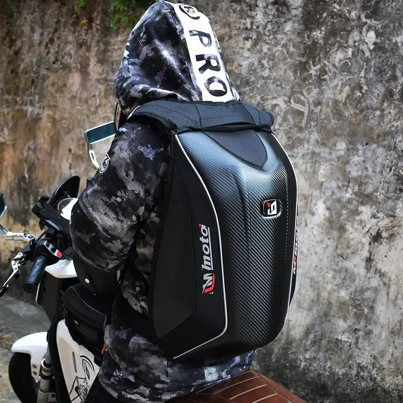 Sac à dos moto en fibre de carbone vu de dos, porté par une personne en tenue camouflage sur une moto, parfait pour le quotidien urbain.