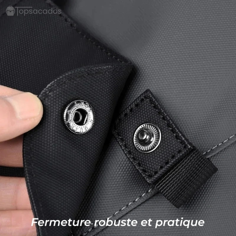 Sac à dos pour étudiant avec gros plan sur la fermeture à bouton-pression métallique sur rabat noir, tenue ferme et facile à ouvrir.