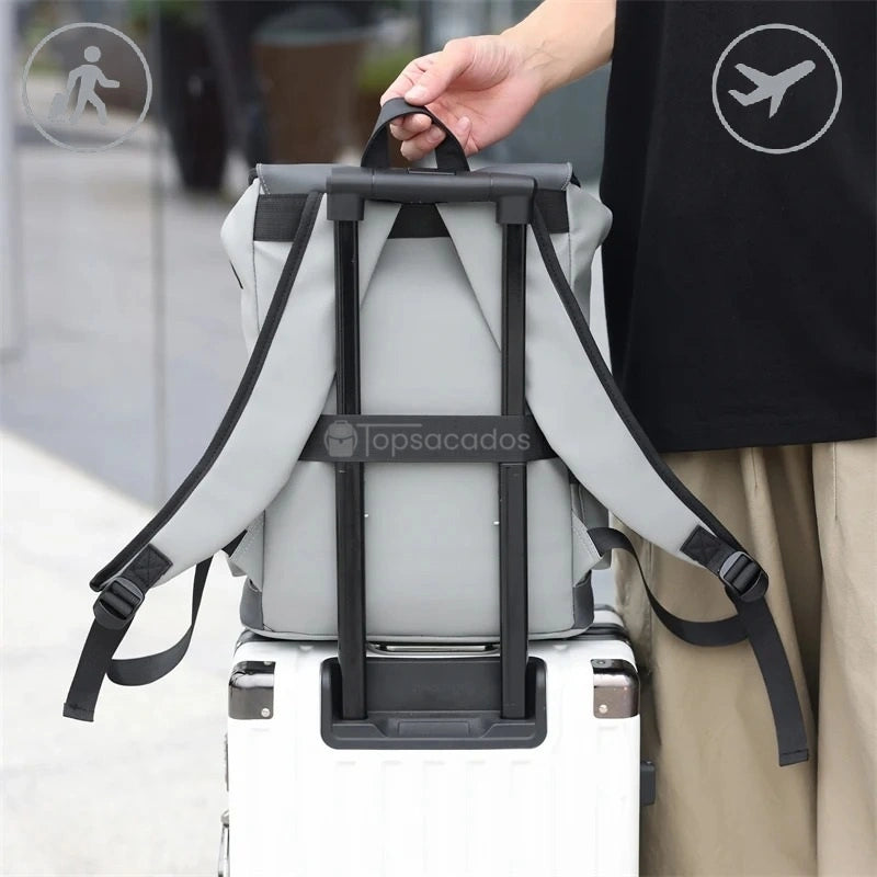 Sac à dos pour étudiant accroché à une valise à roulettes à l’aide d’une sangle horizontale, en situation de voyage urbain.