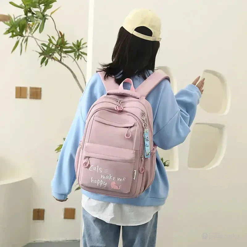 sac a dos primaire rose porté par une élève en intérieur, vue de dos, ambiance scolaire décontractée