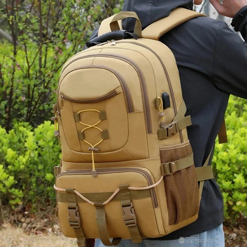 Sac à dos rando kaki porté par un randonneur en extérieur, avec végétation en arrière-plan