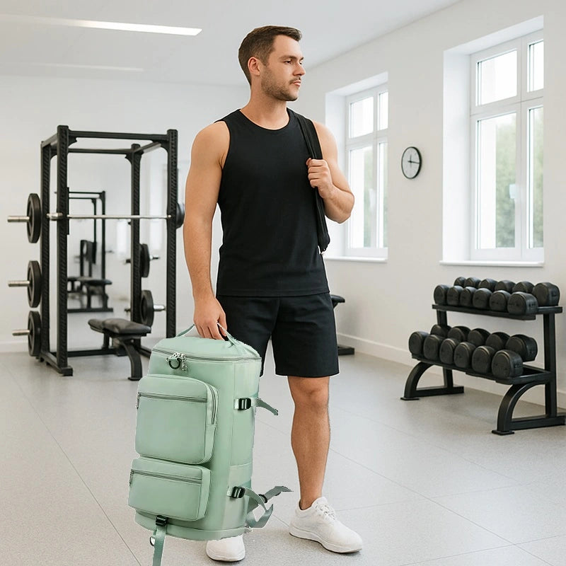 Sac à dos sport grand volume porté à la main par un homme en tenue de sport dans une salle de musculation équipée de poids et machines.