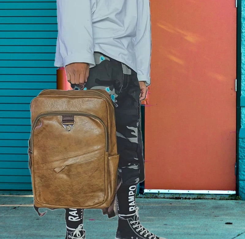 Sac à dos ville homme porté à la main par un homme en tenue urbaine, en environnement citadin coloré.