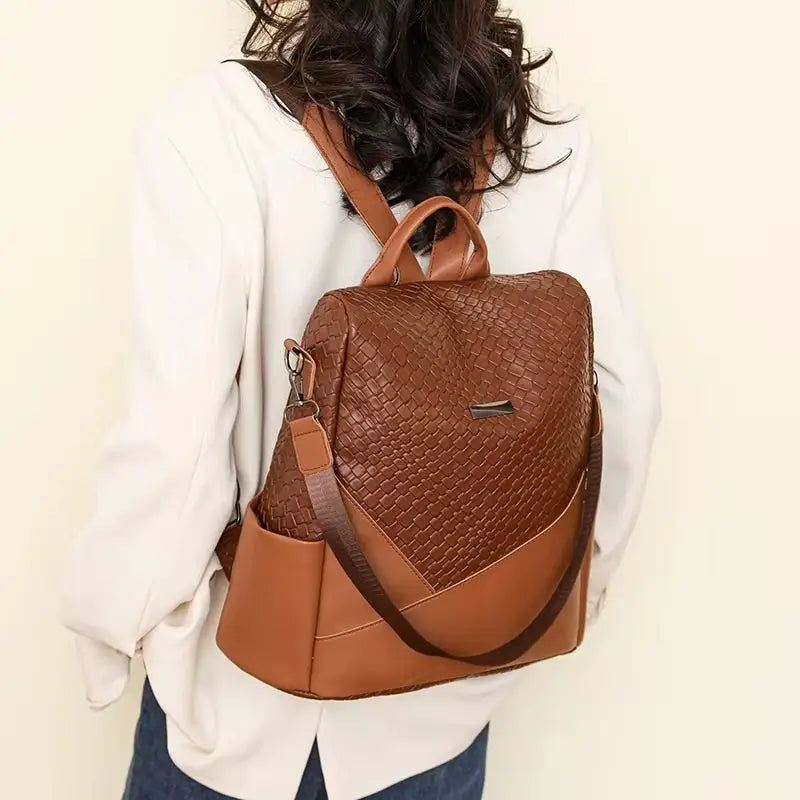 Sac à dos marron Femme porté sur les épaules d’une femme en chemise claire, en intérieur sur fond beige doux.